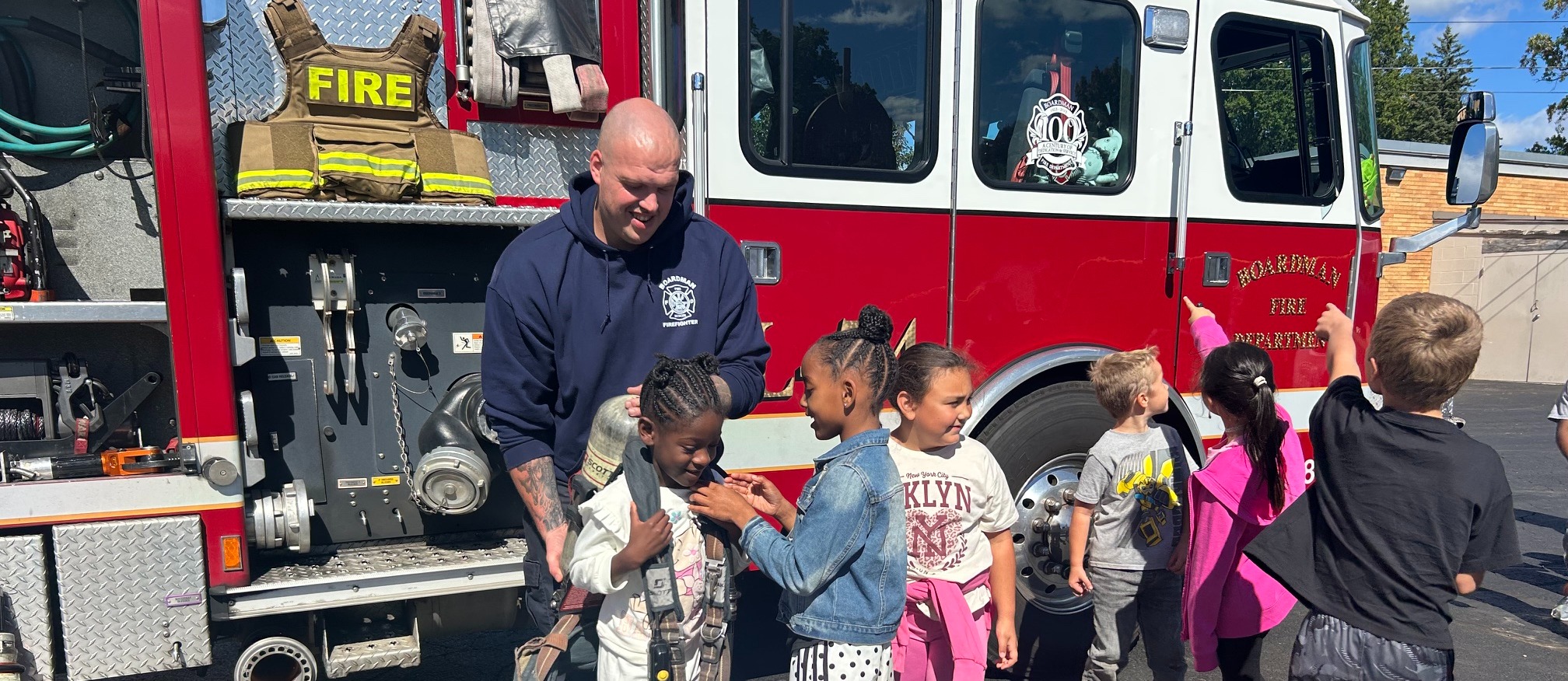 fire fighter with students in front of fire truck for a fire prevention visit