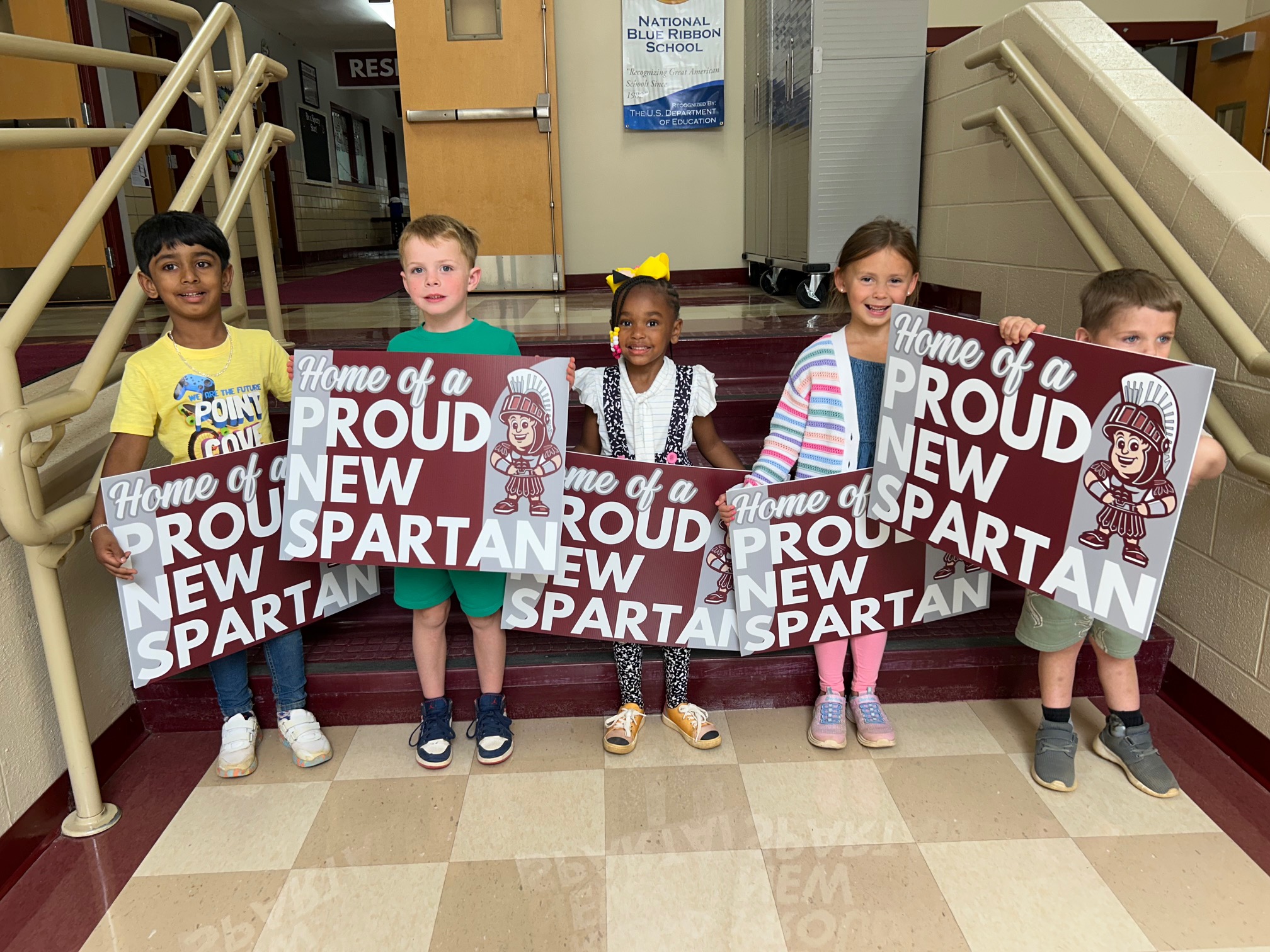 kindergarteners holding  Proud to Be a New Spartan yard signs