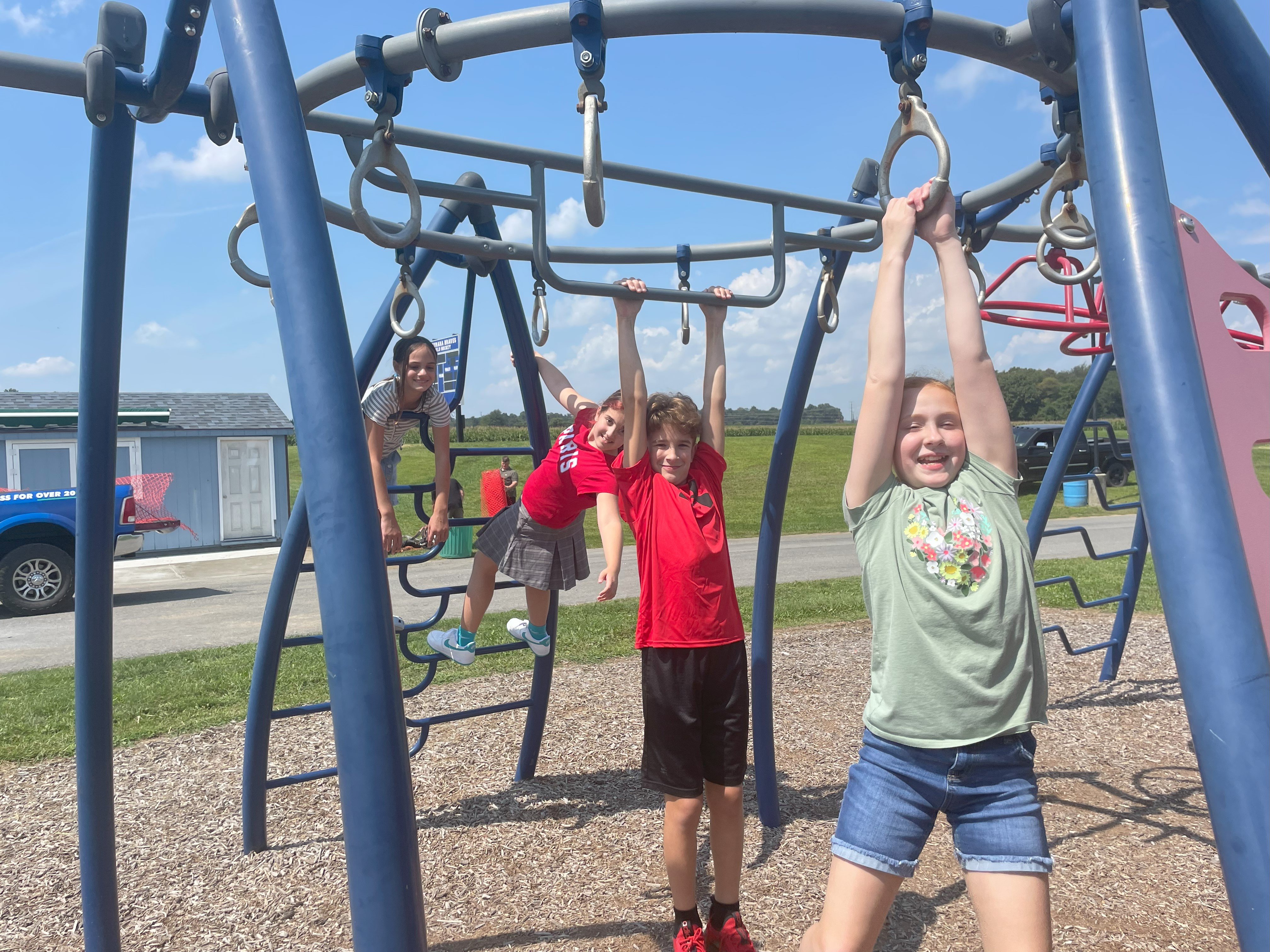 students playing on playground handing on monkey bars