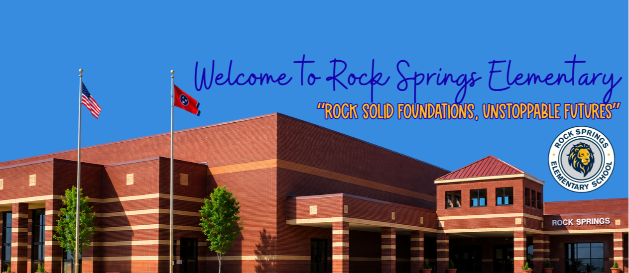 A large school building with brick walls, a red roof, and green lawn. Flags on poles and a blue sky.