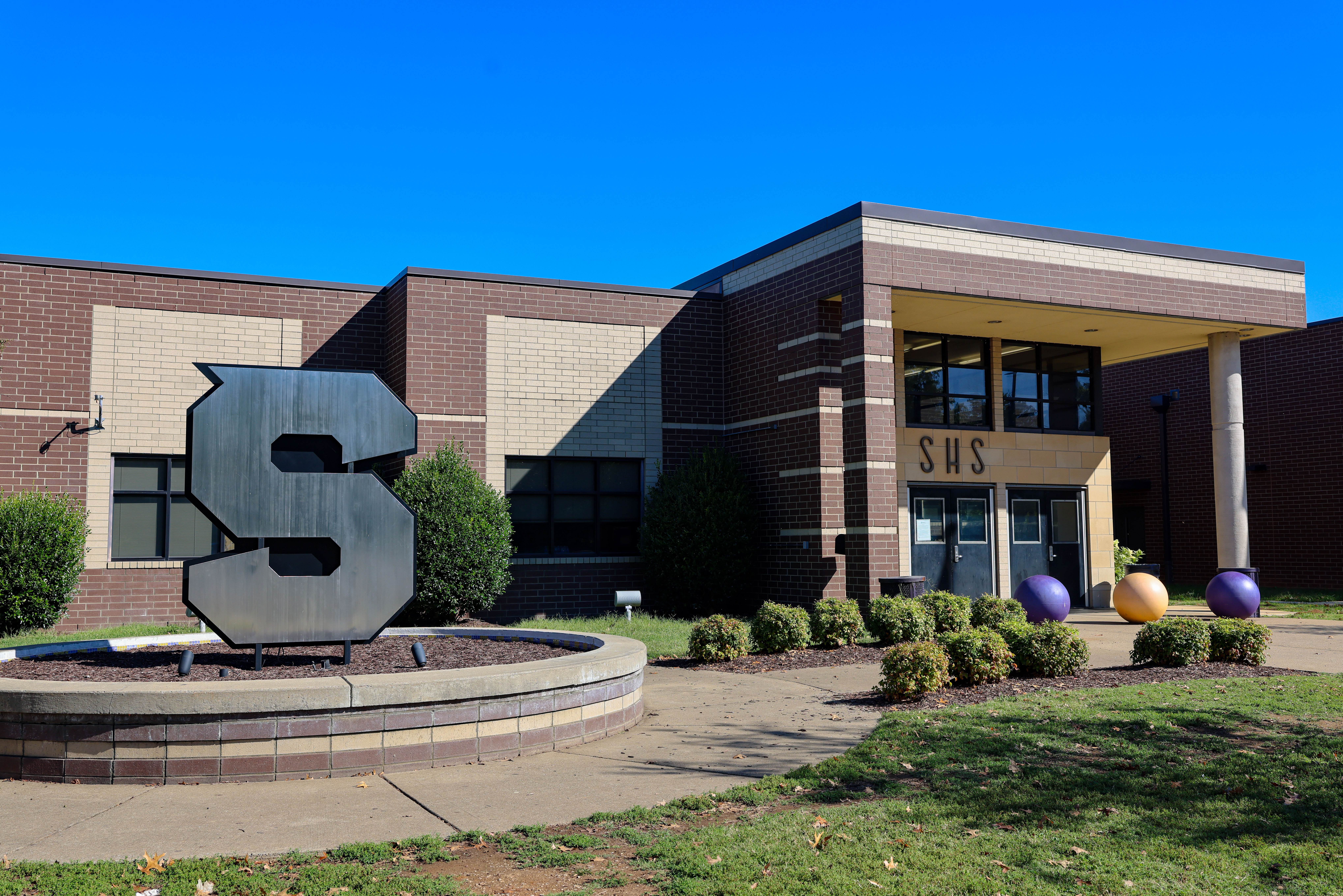 Brick building with letters S H S on exterior with large fountain