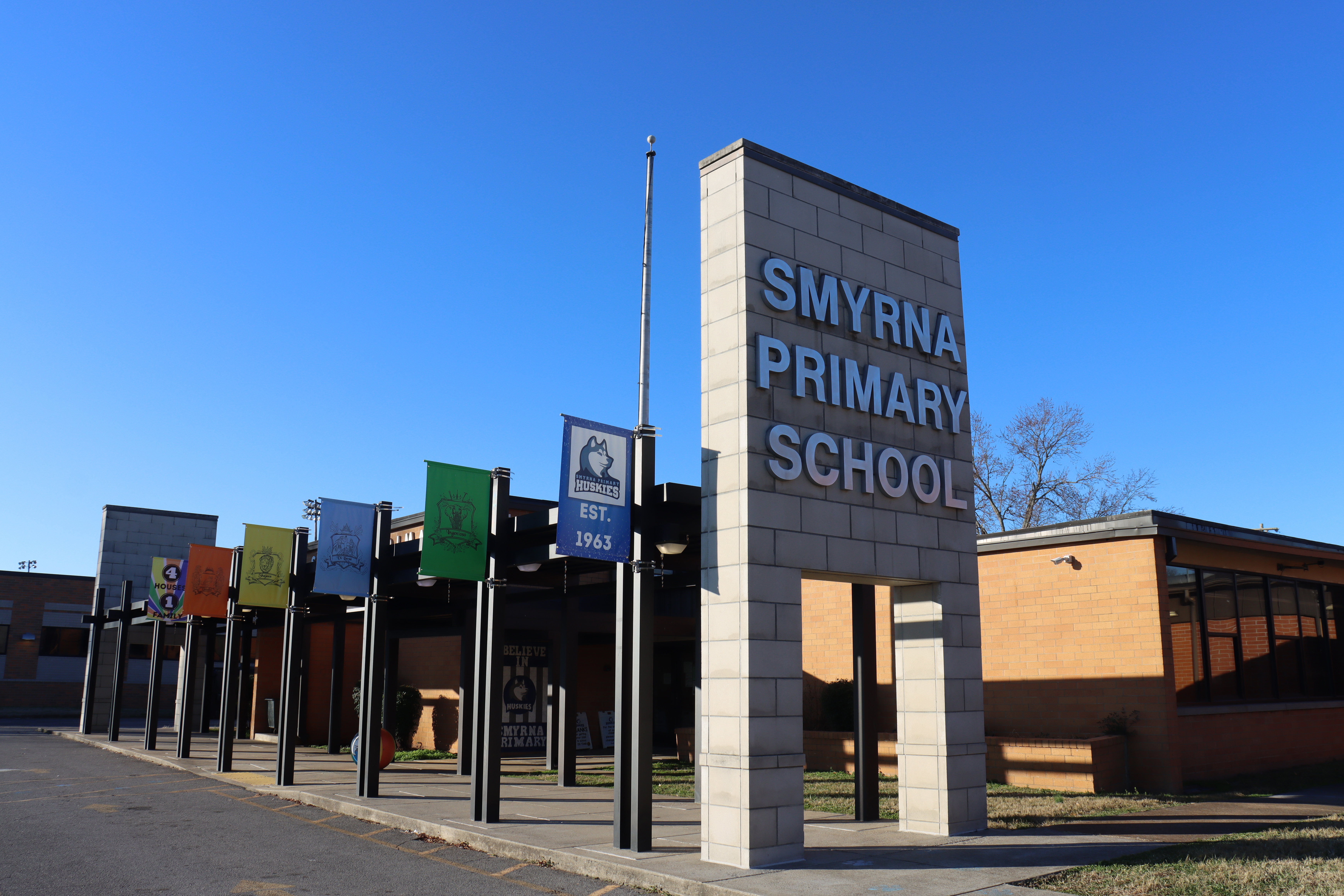 School entry sign that says Smyrna Primary School with various flags at  entrance