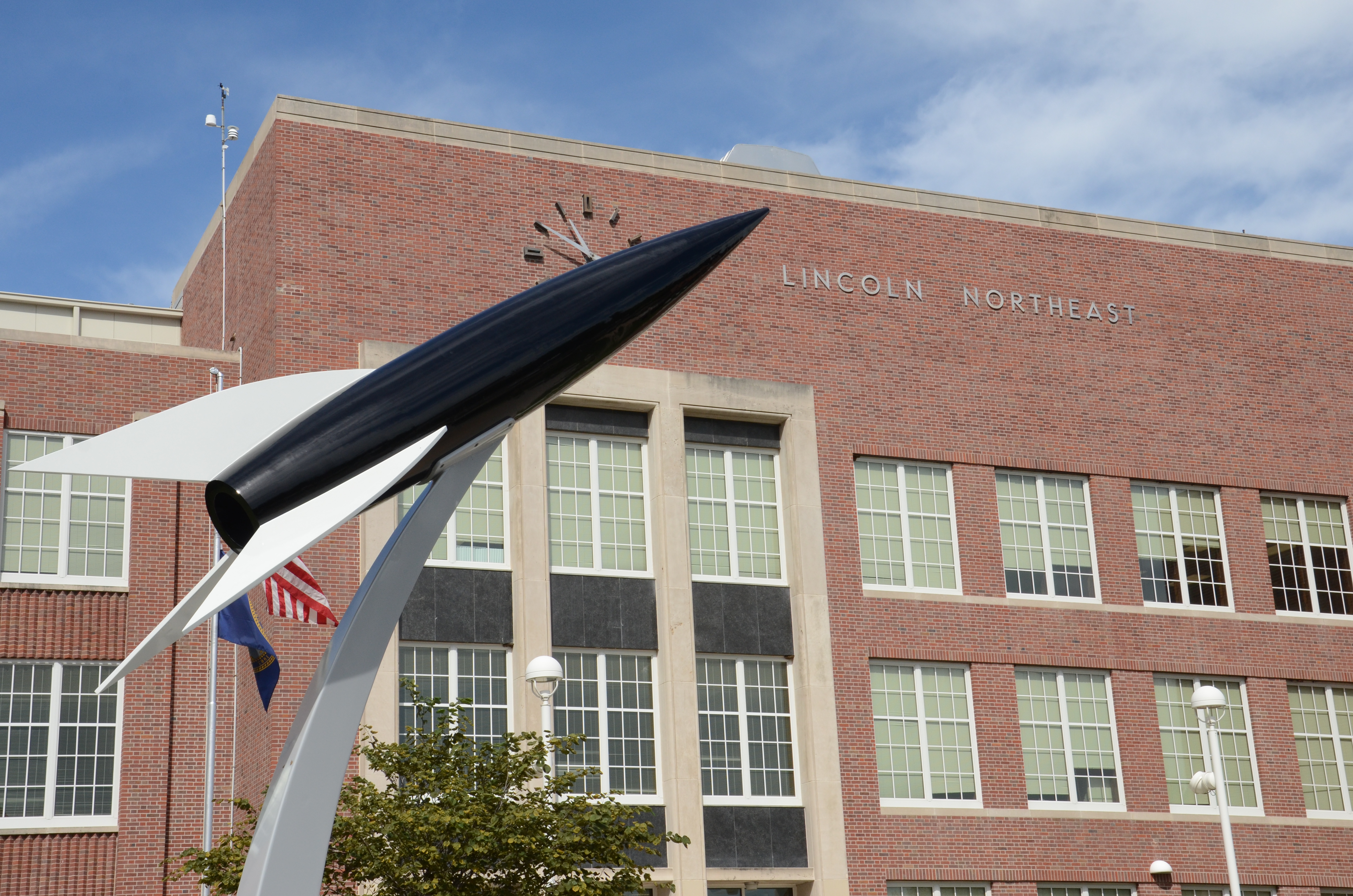 Front entrace of Lincoln Northeast High School with a rocket model in the foreground