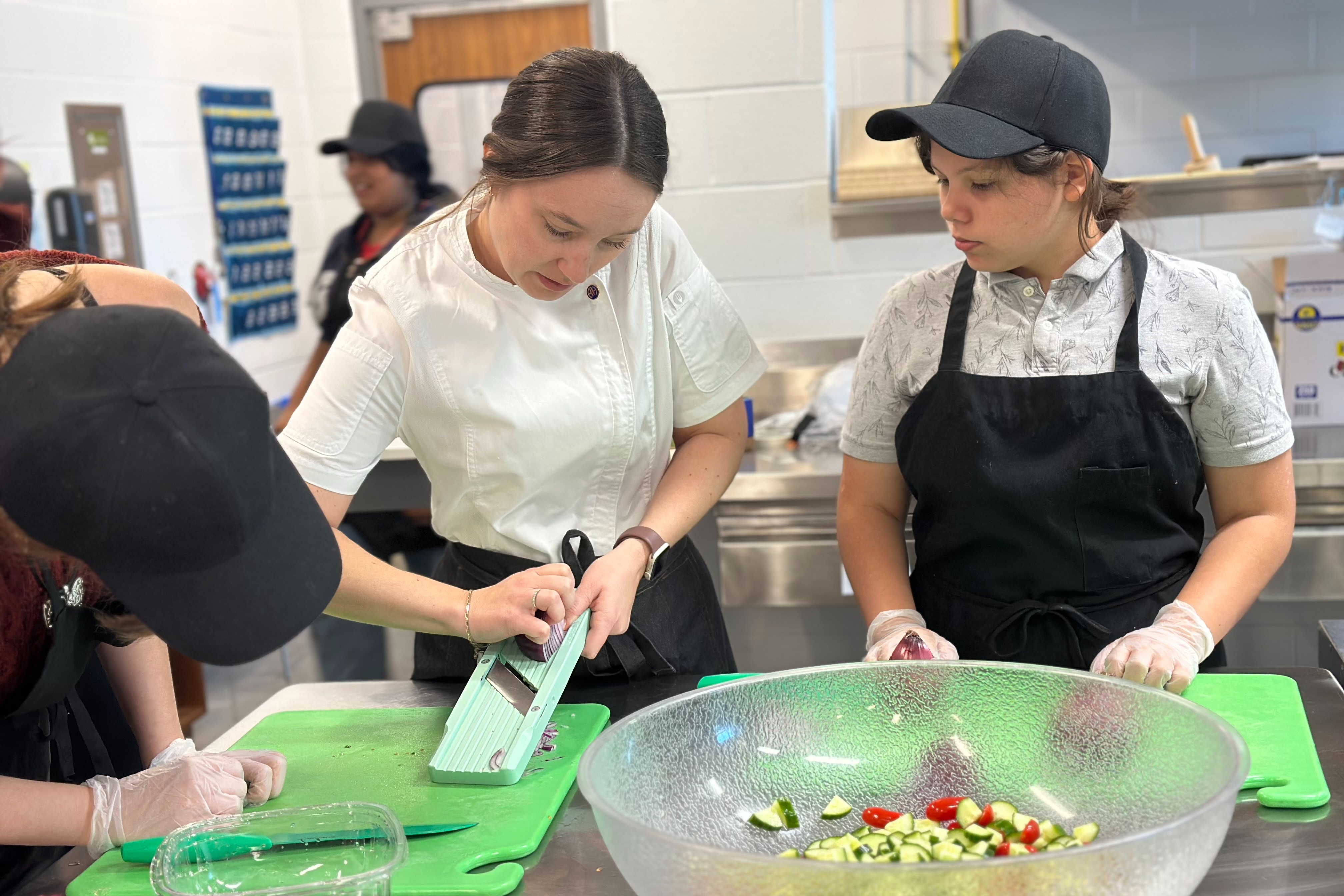 Culinary teacher demonstrating technique to two students