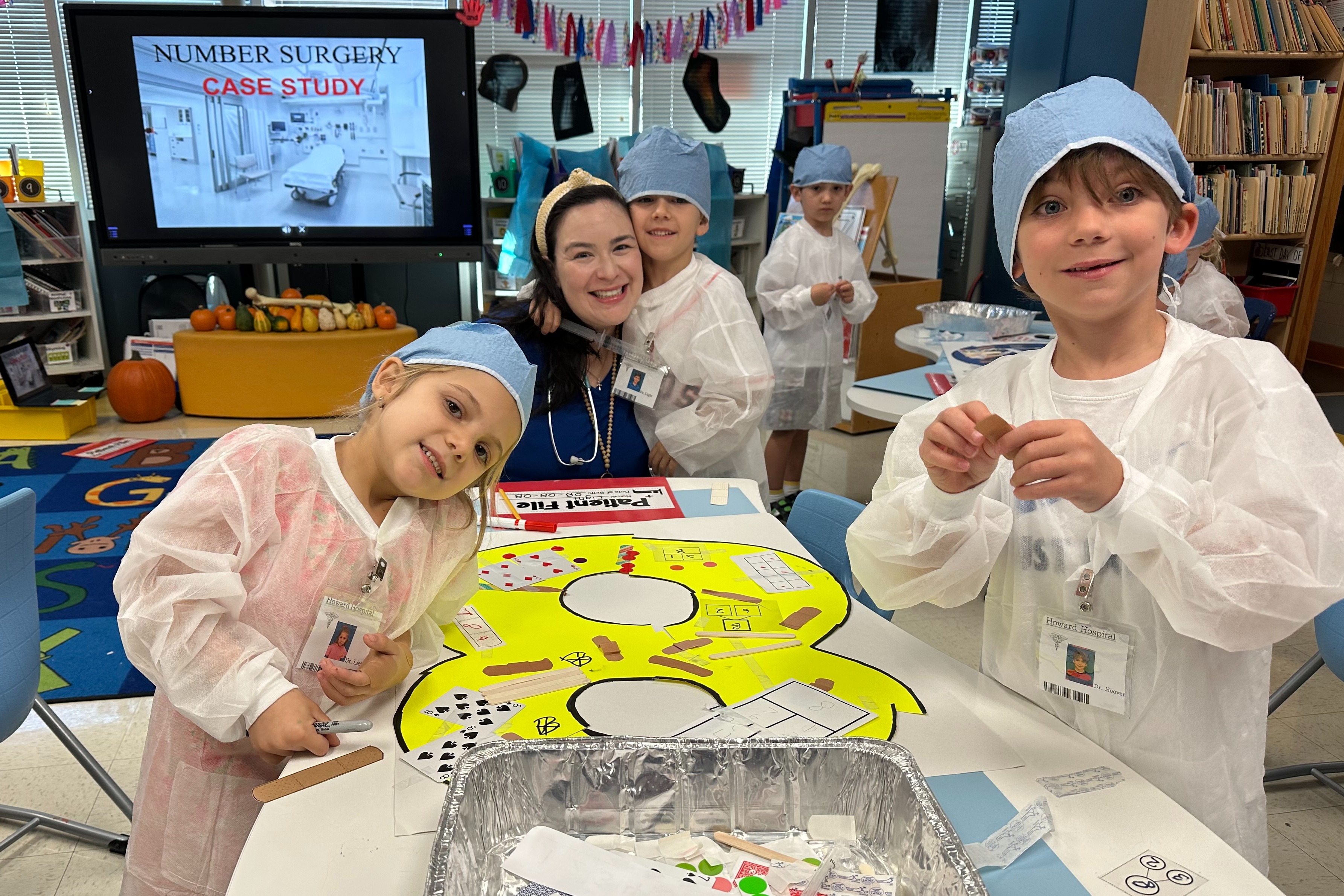 Teacher and three early childhood students dressed in scrubs and caps to perform number surgery