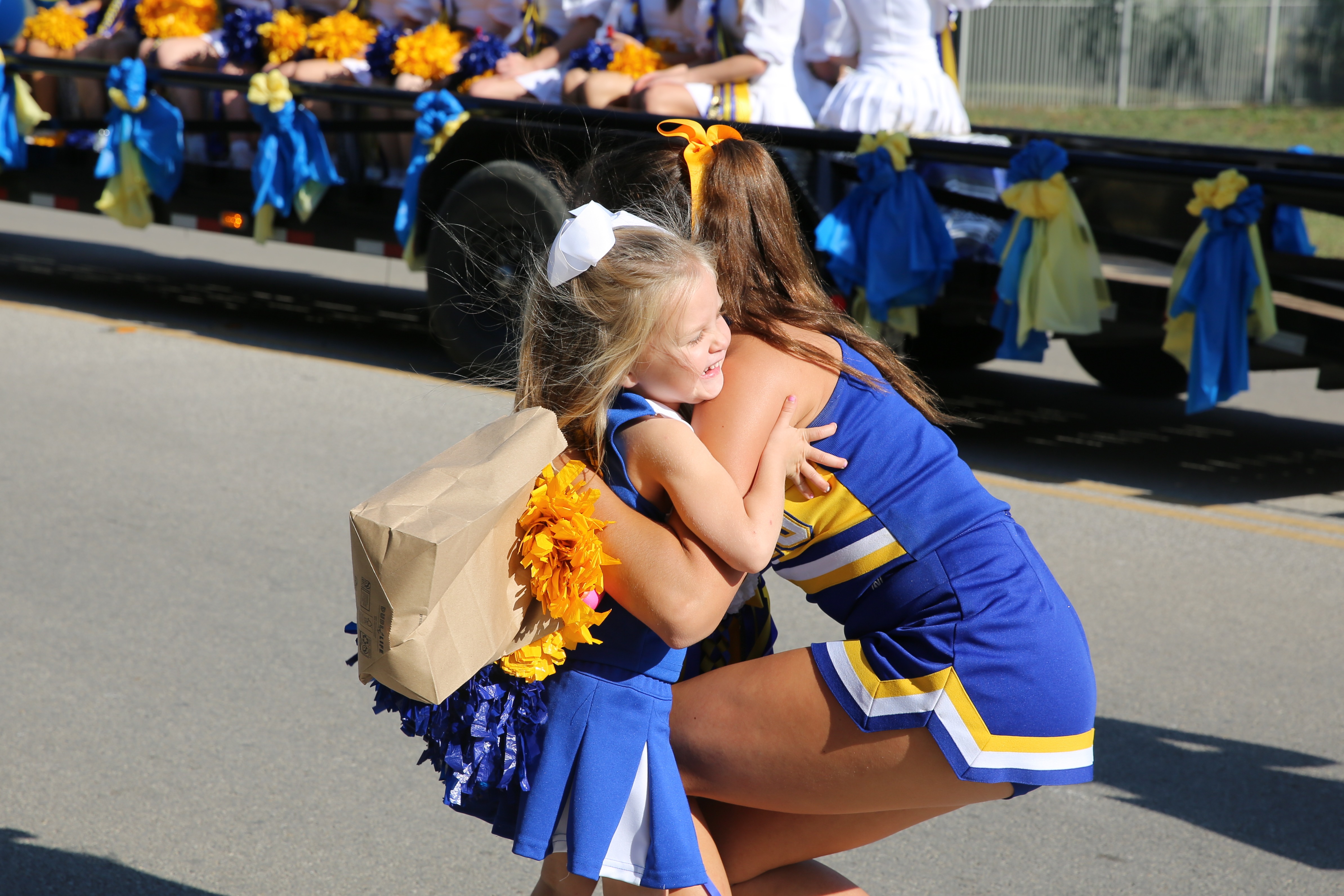 Cheerleader hugging little girl dressed as cheerleader at Howdy Parade