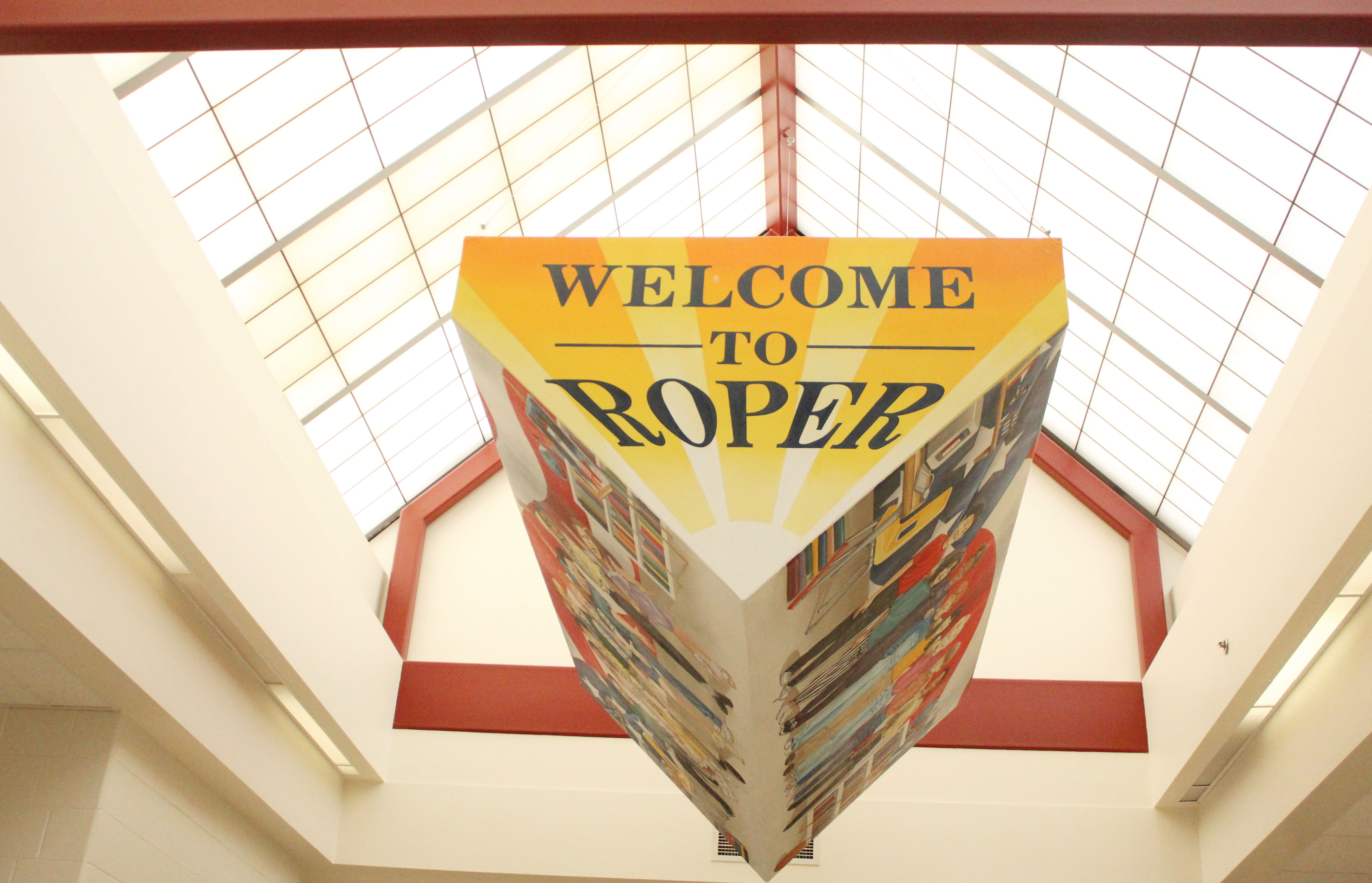 Triangular sign hanging from the skylight in the Roper hallway saying "Welcome to Roper Elementary"