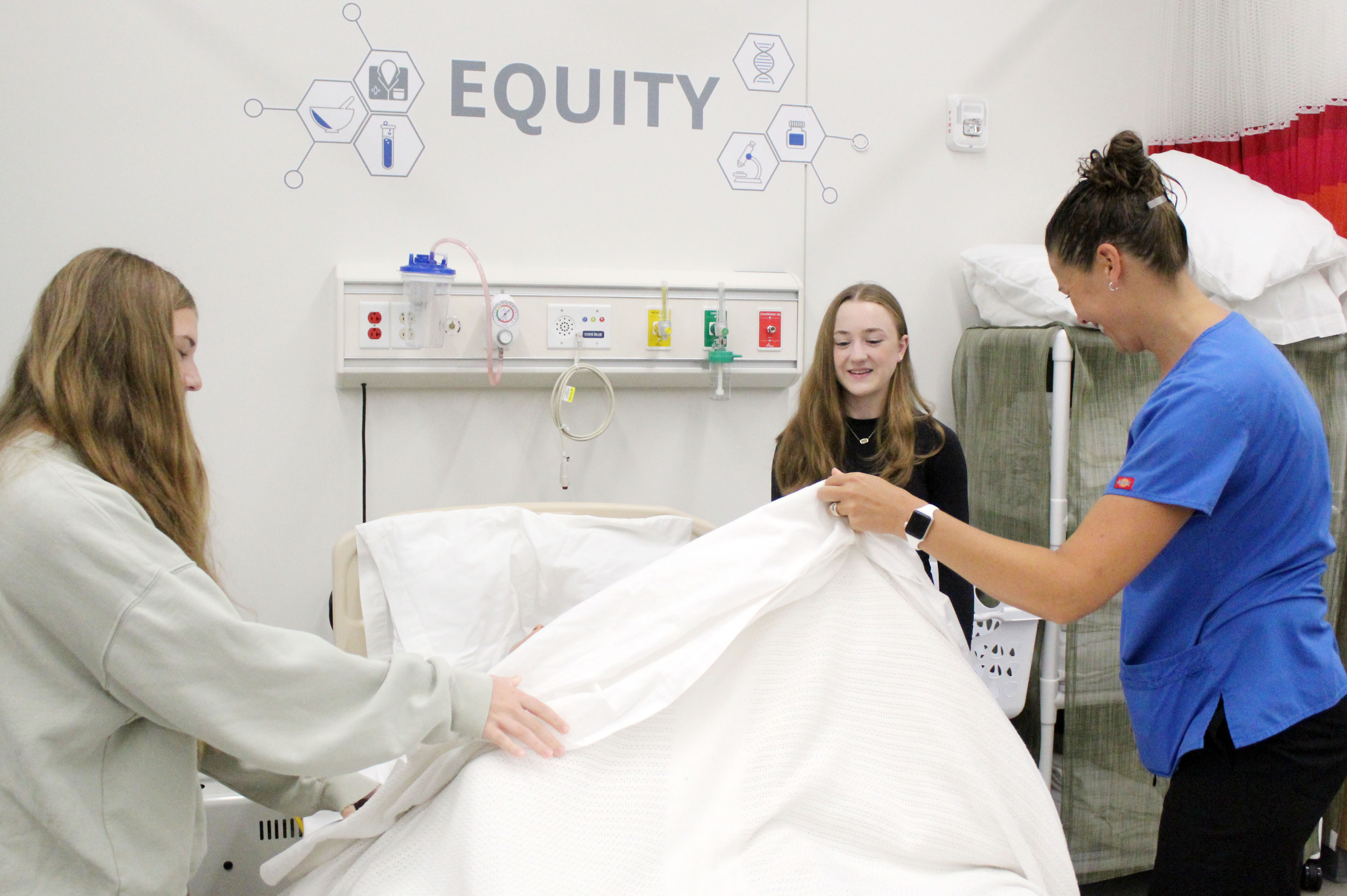 Students working learning how to work with a patient and hospital bed