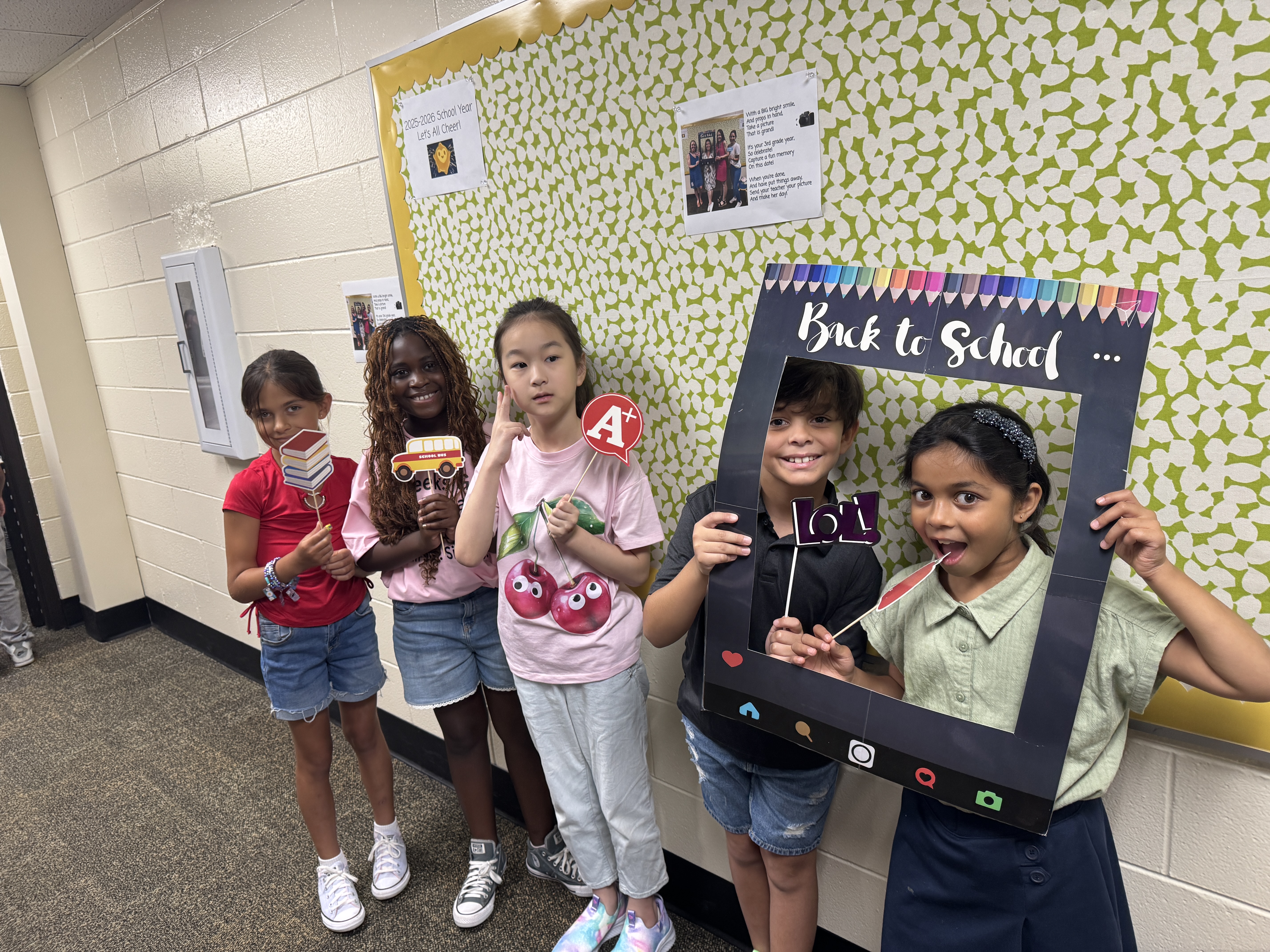 Students standing in the hallway with photo props for the first day of school