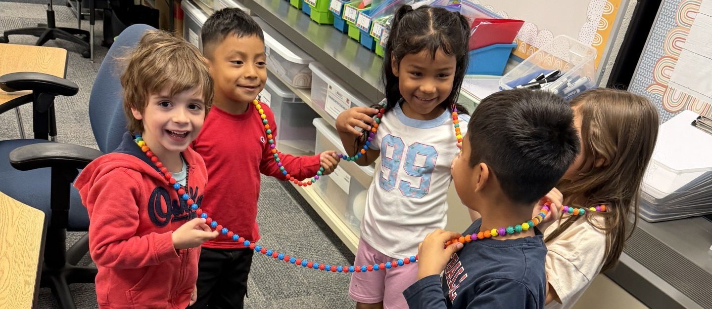 Students smiling and connected by a big necklace