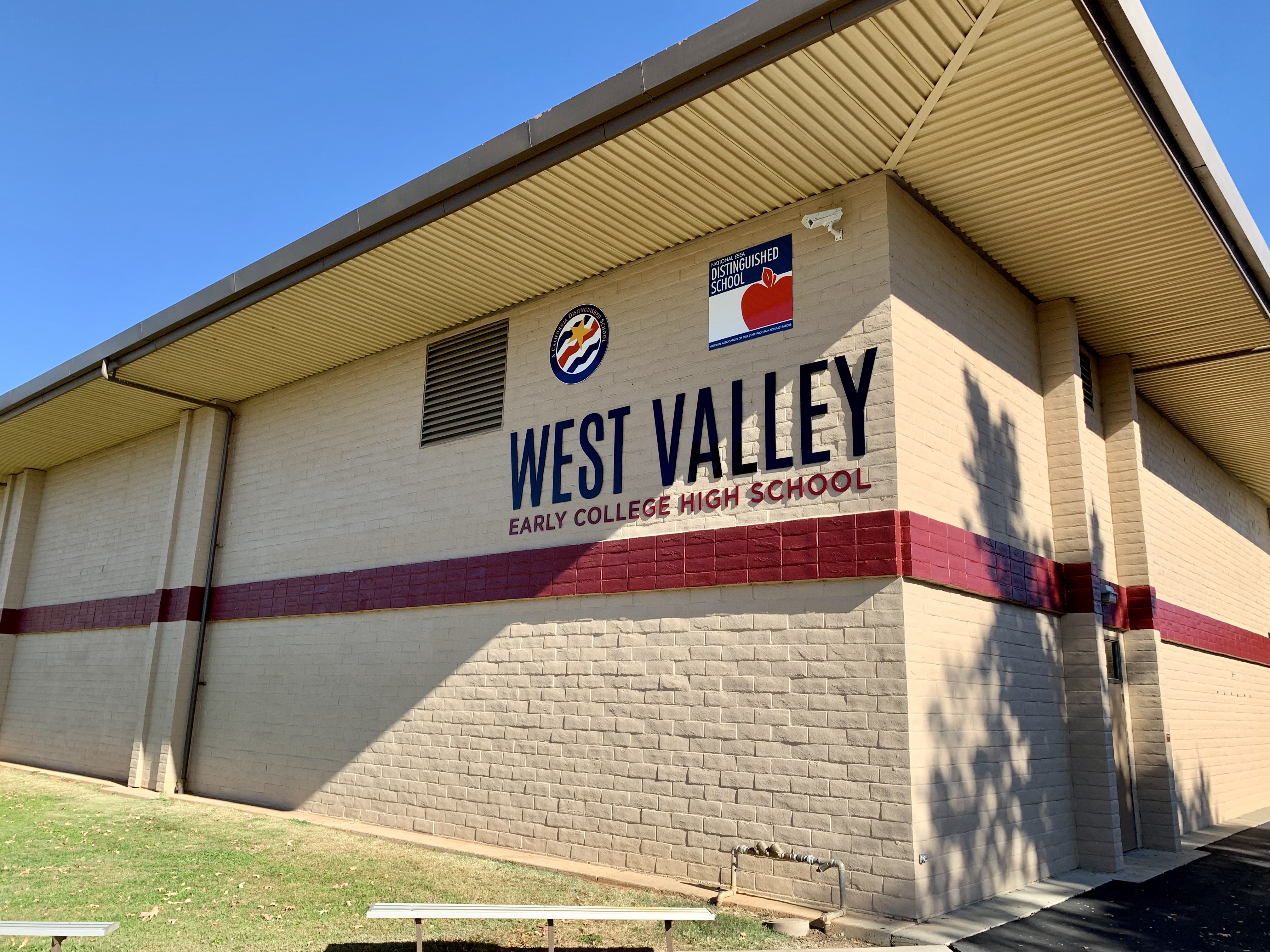 A light brown building displays "West Valley Early College High School" in blue and red letters. Two benches are in front.