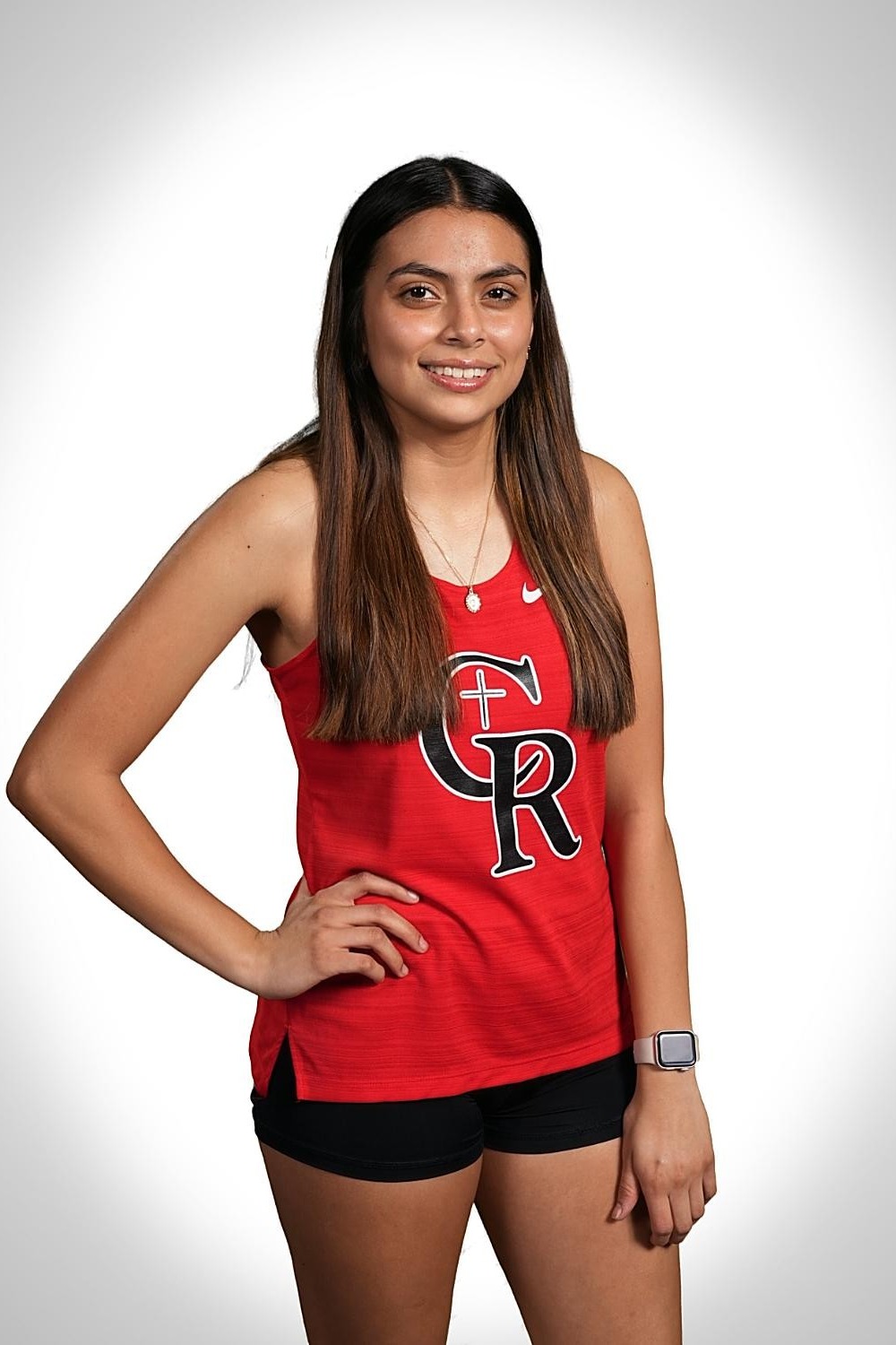 A woman with long hair poses in a red tank top with GR and a cross logo.