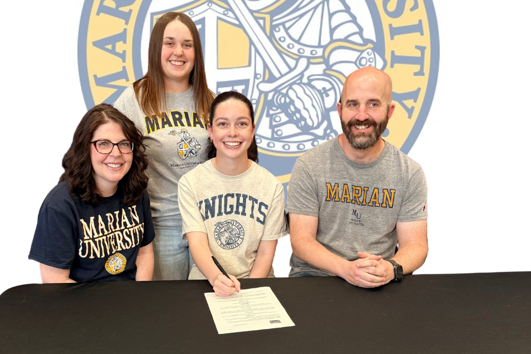 Four people sit at a table with a document, smiling. Two wear glasses, and two wear school uniforms. Behind them, a logo reads "MARGARET BLOOMER SIGNED CHEERLEADING".