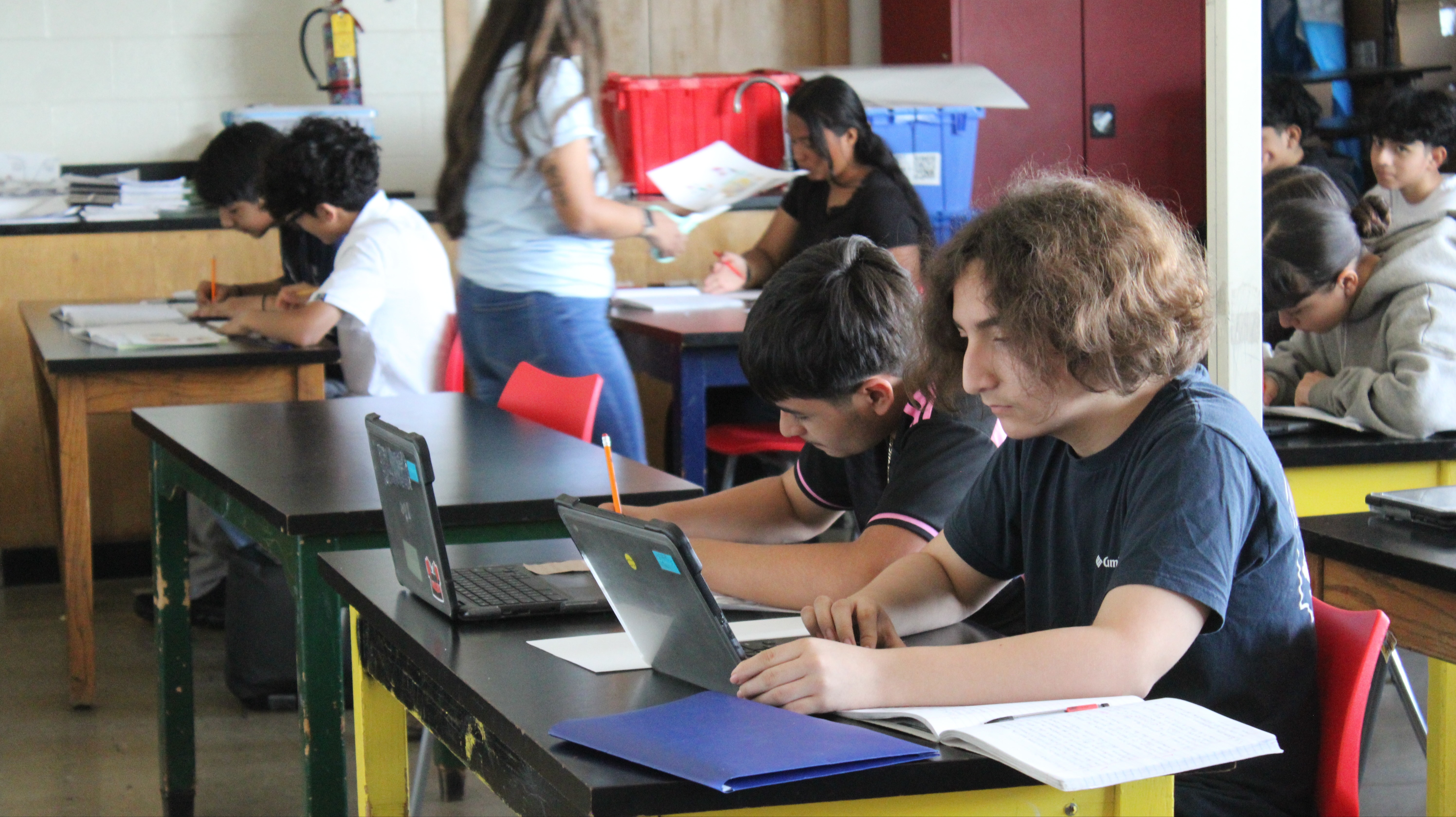 Students seated at their desks, actively engaged in a digital lesson on their Chromebook laptops.students seated at their desks, actively engaged in a digital lesson on their Chromebook laptops.