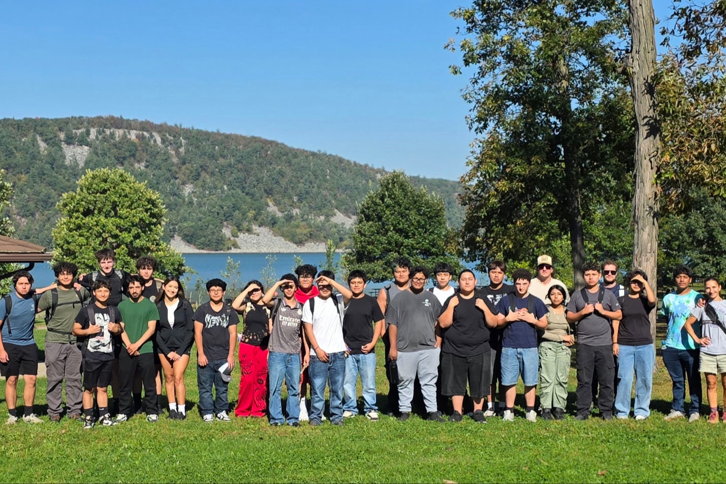 A group photo of Adventure Club members smiling and posing together during an outdoor excursion, surrounded by a scenic nature backdrop.