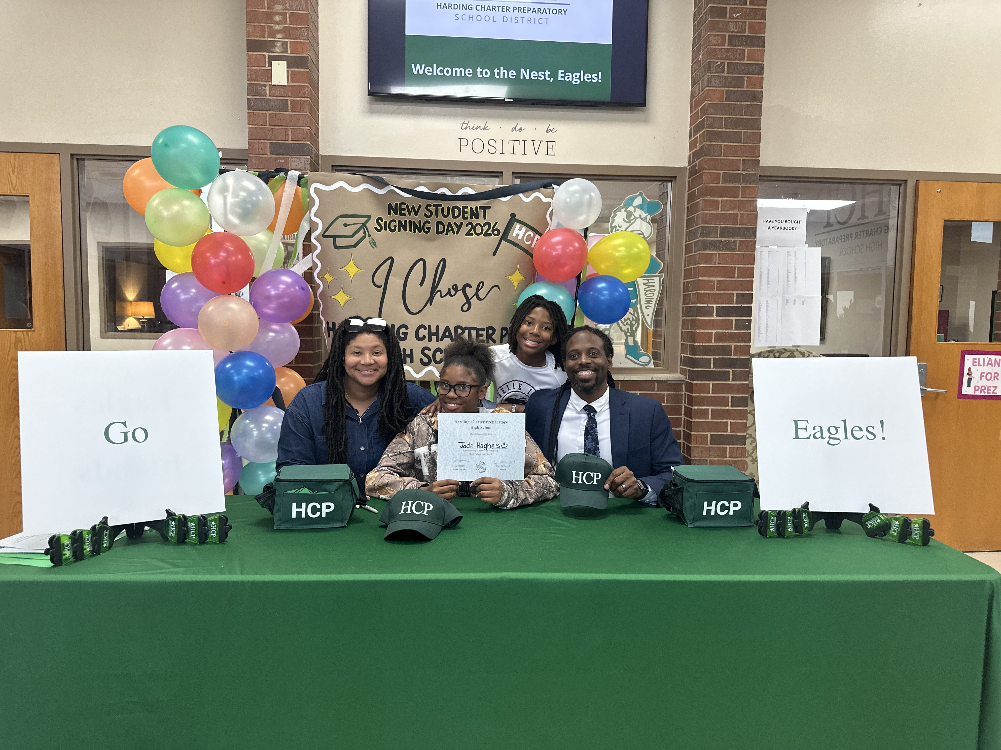 A family happily smiles as an incoming freshman holds up her HCPHS Signing Day certificate.