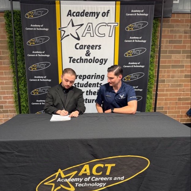 Academy of Careers and Technology student Austin Roark signs a letter of intent to join the United States Air Force while his recruiter looks on.