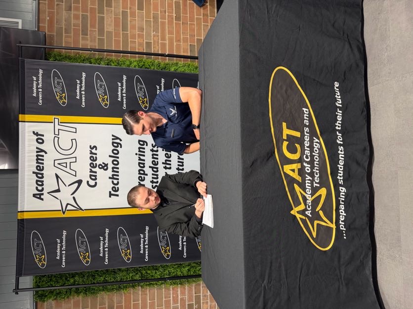 Academy of Careers and Technology student Austin Roark signs a letter of intent to join the United States Air Force while his recruiter looks on.