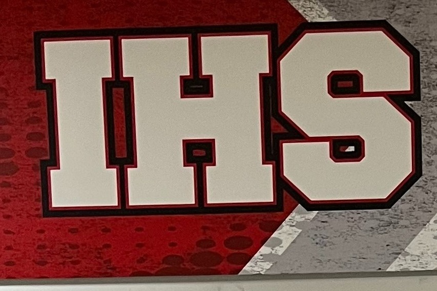 Two men stand in front of a red and white booth, with "IHS Student Opportunities" on it.