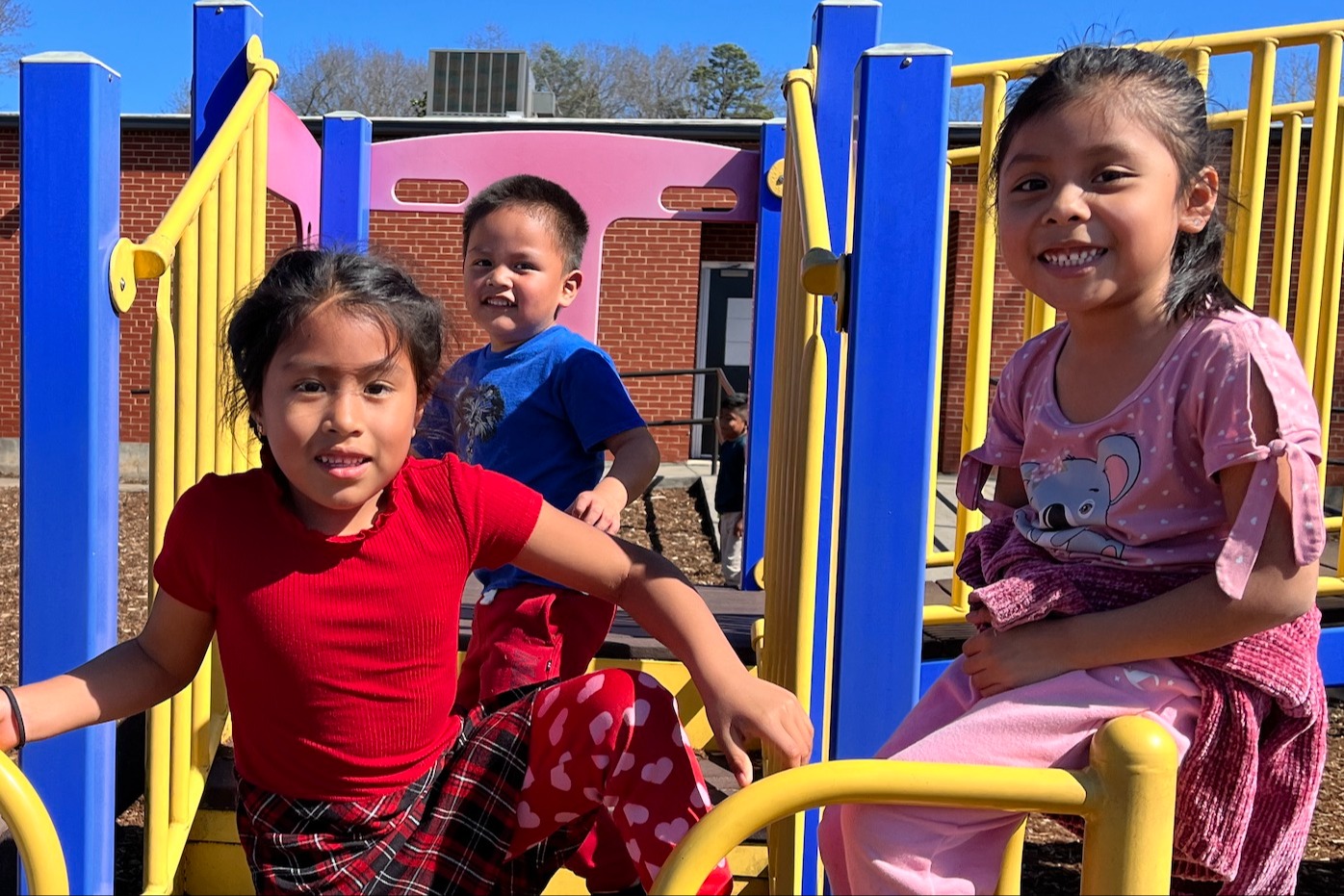 three early school age students playing on a playground