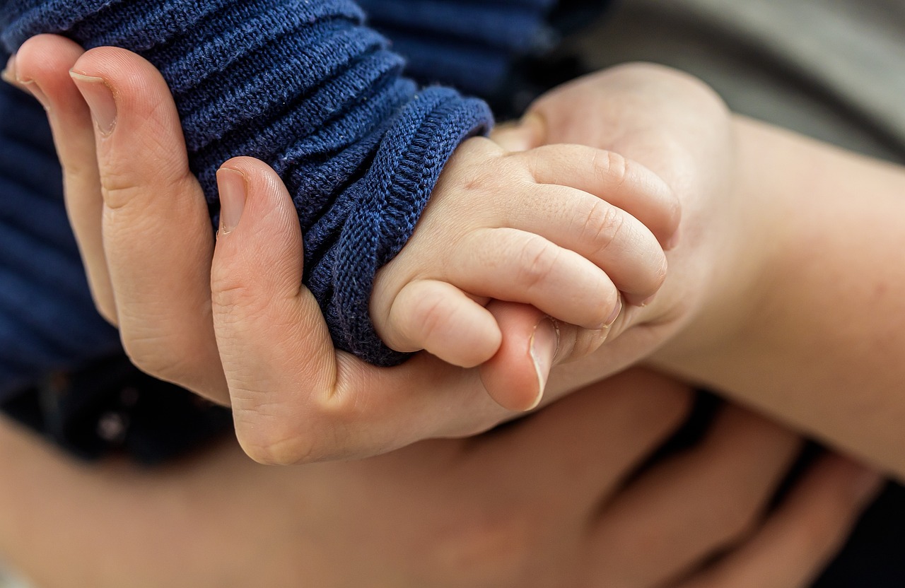 Close up of parent holding an infant's hand