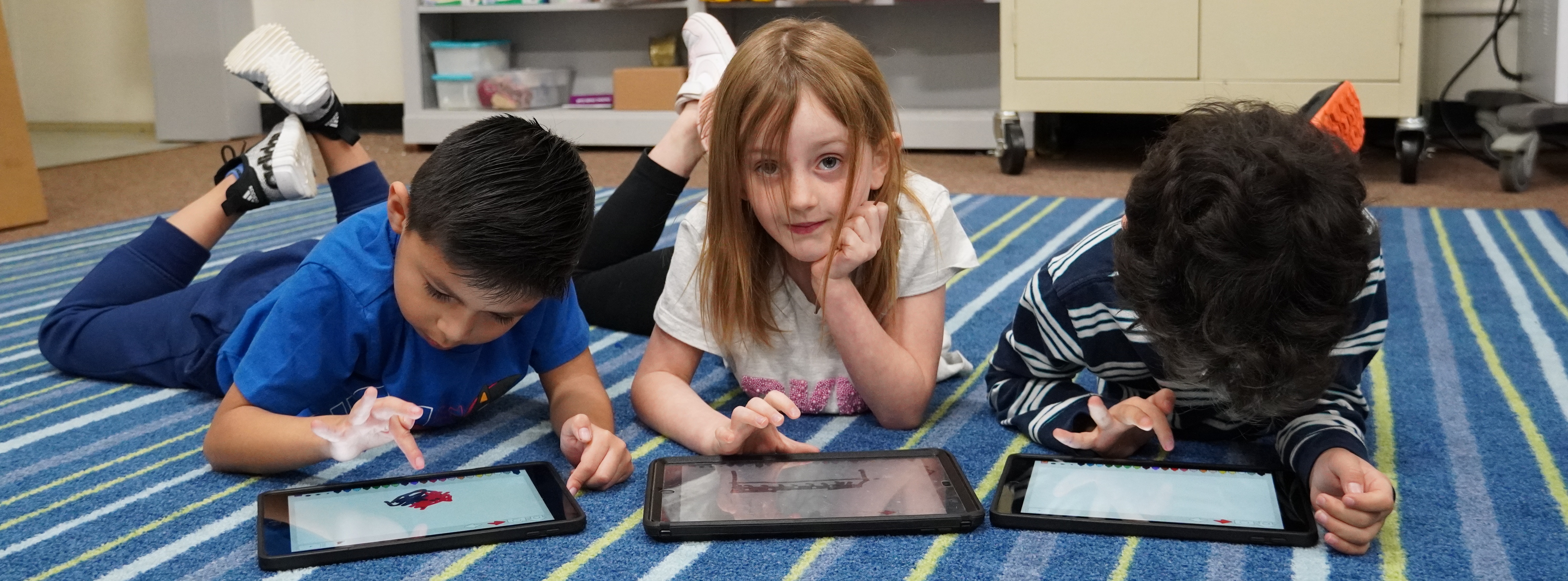 students working on a tablet on the floor