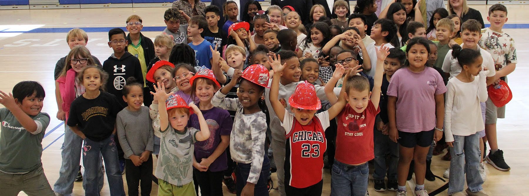 group of students with hands up in the gym