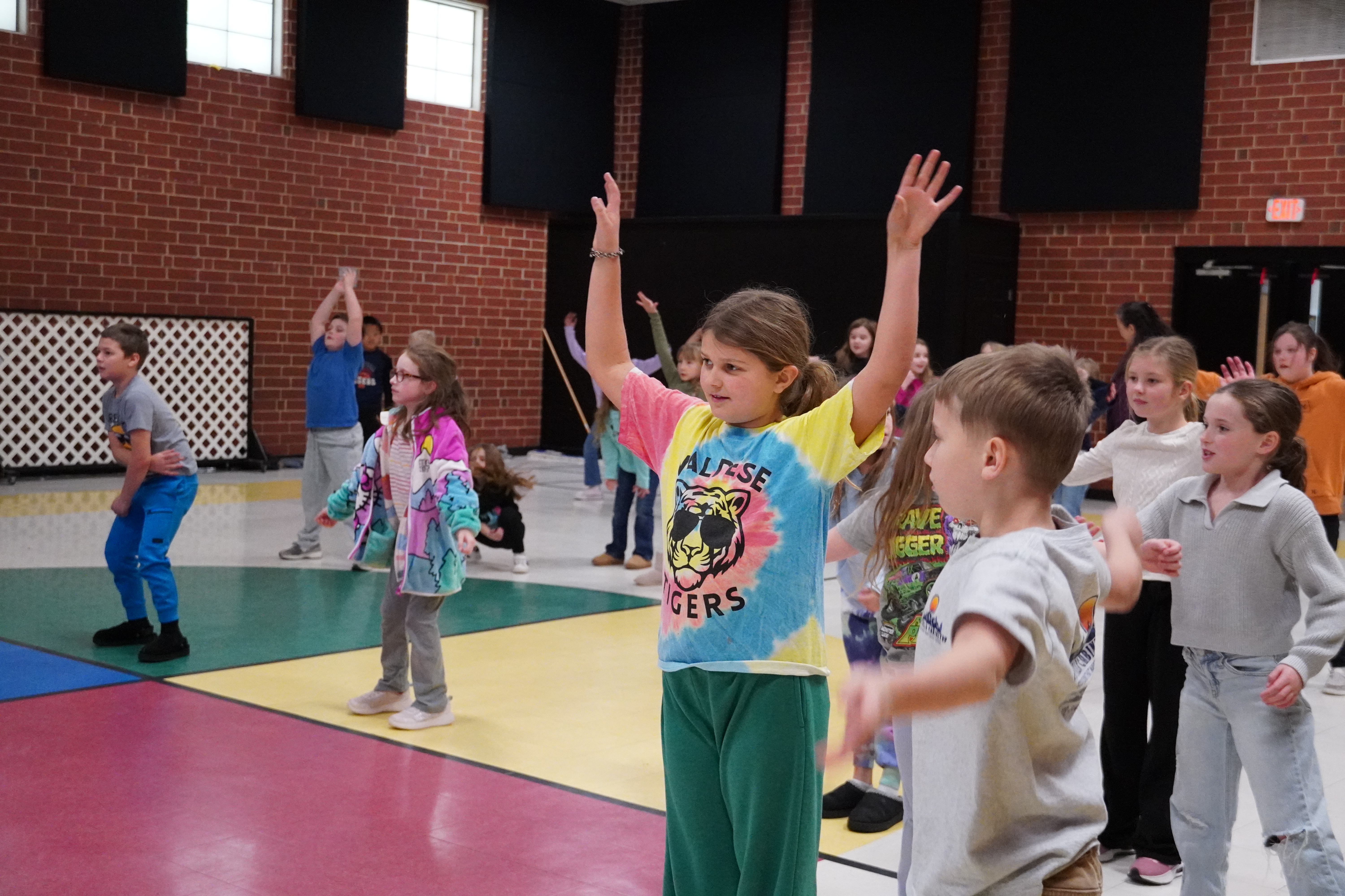 students raising hands in the gym