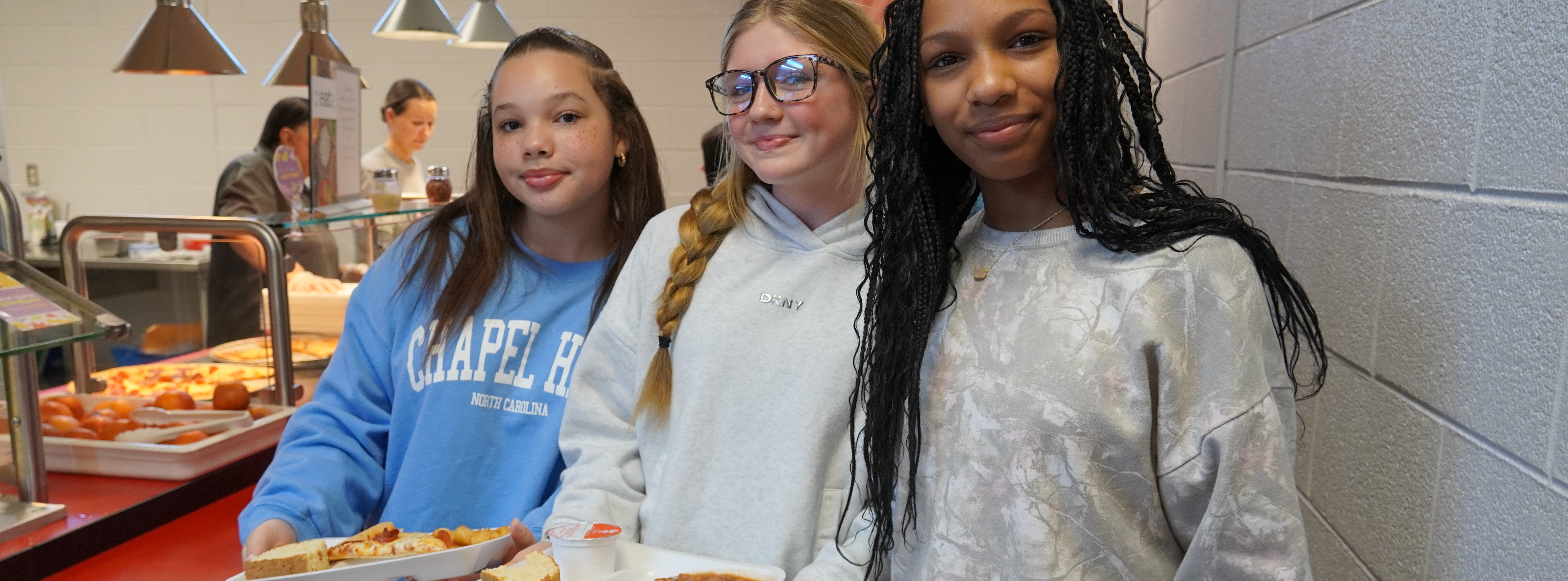 students in the lunchroom with trays of food