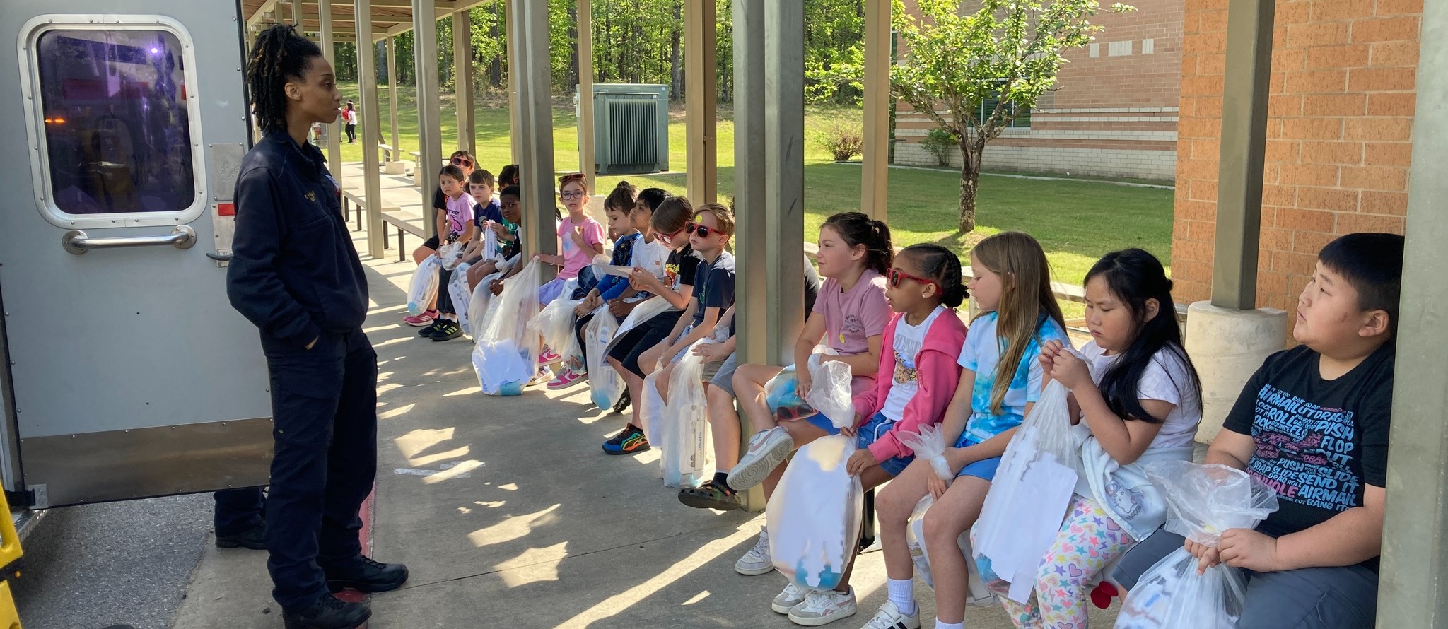 Students learning outside from a first responder.