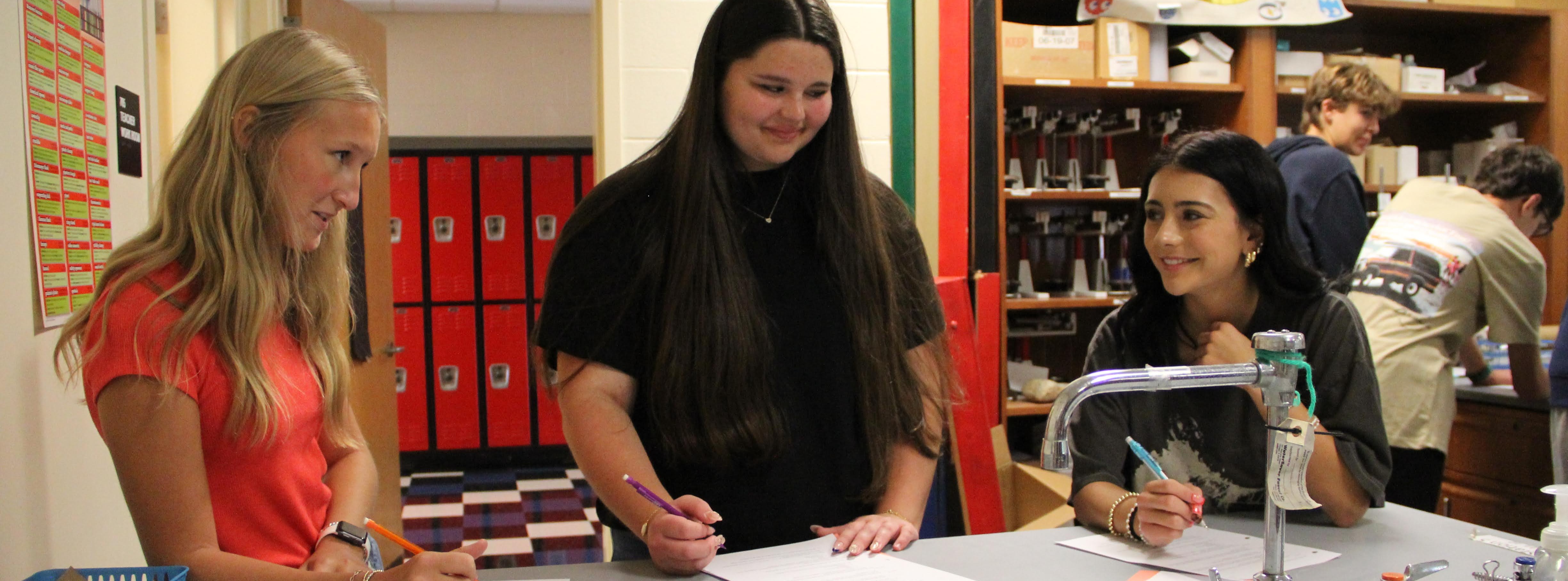 students at a table working on a sheet of paper