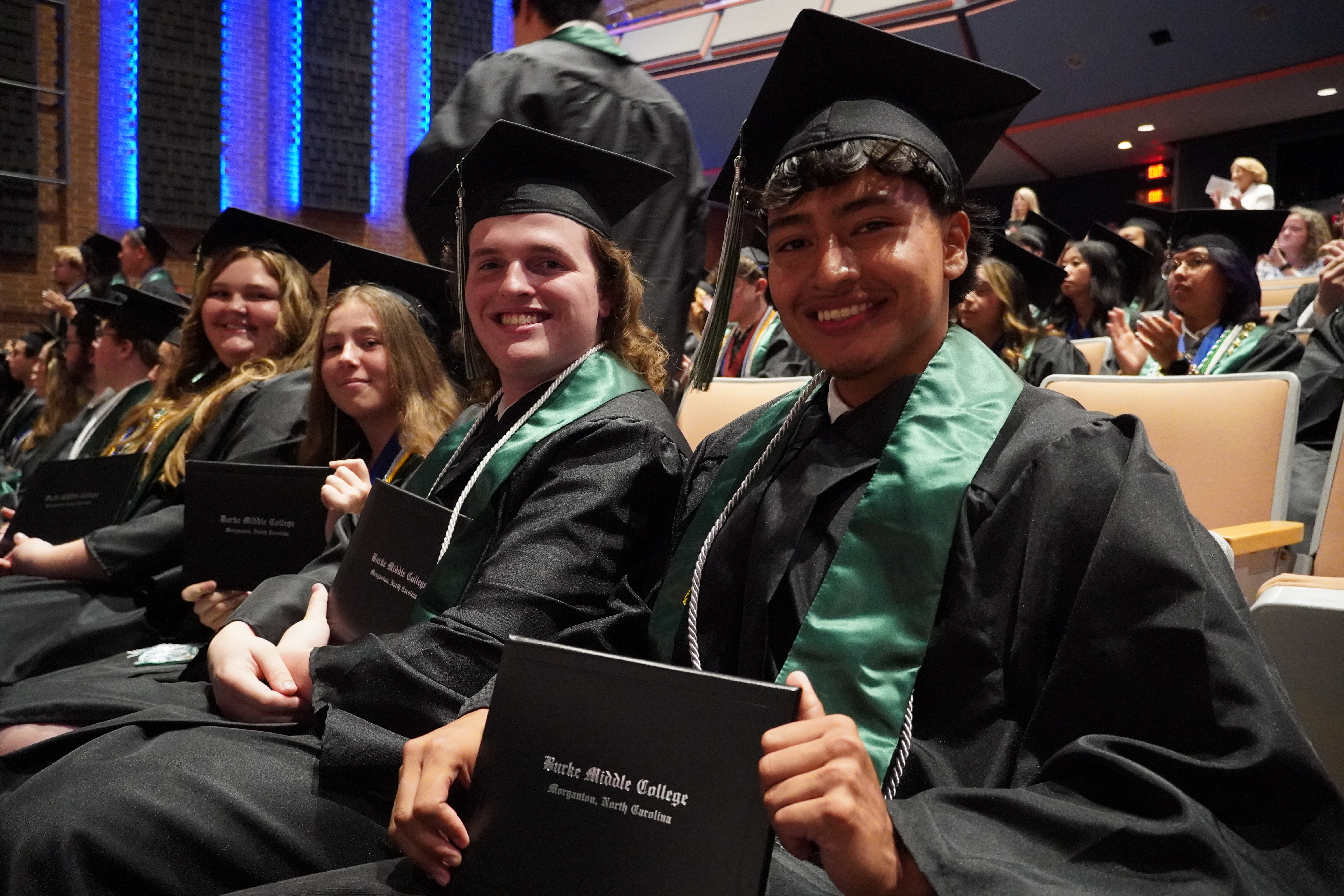 students smiling holding diploma at graduation