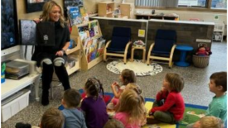Children in GSRP sitting on colorful carpet while a staff member reads them a story