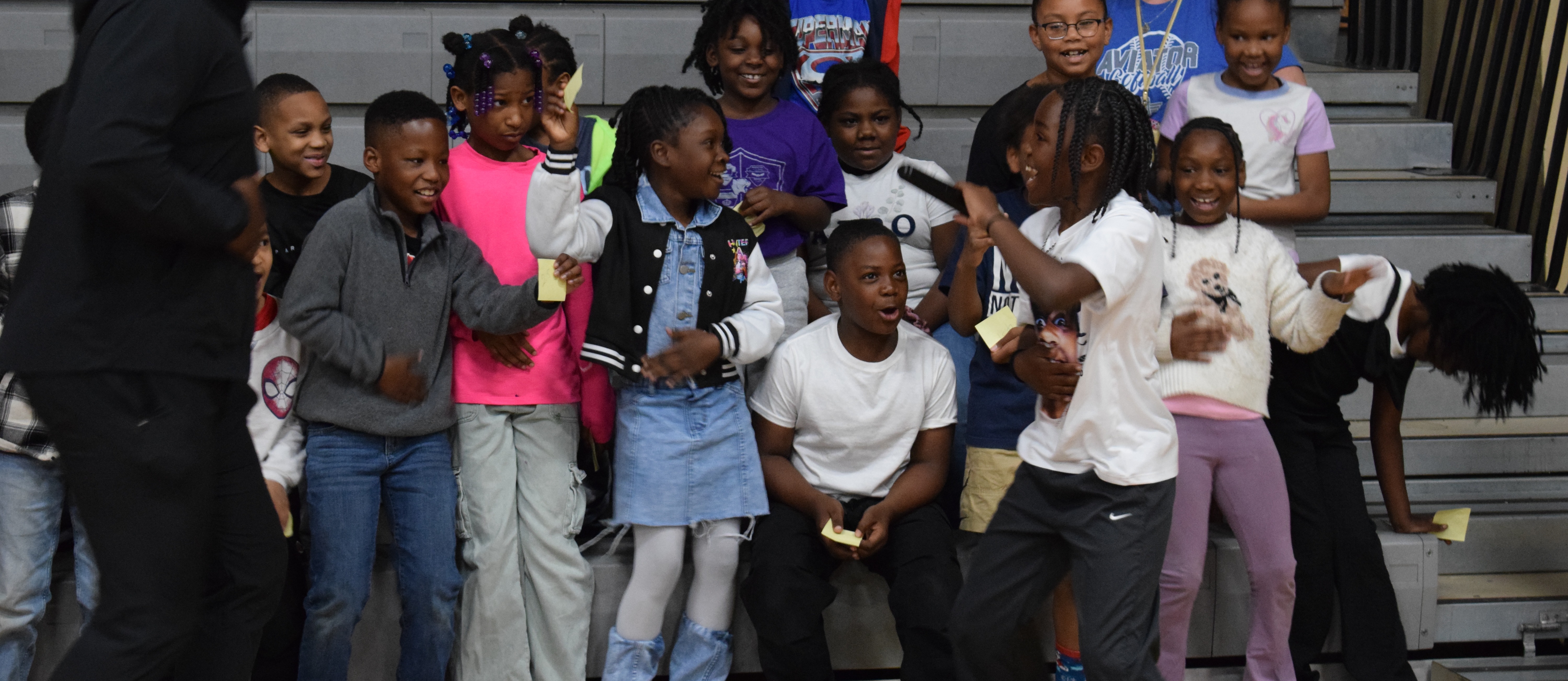 Students excitedly dancing in gym bleachers.