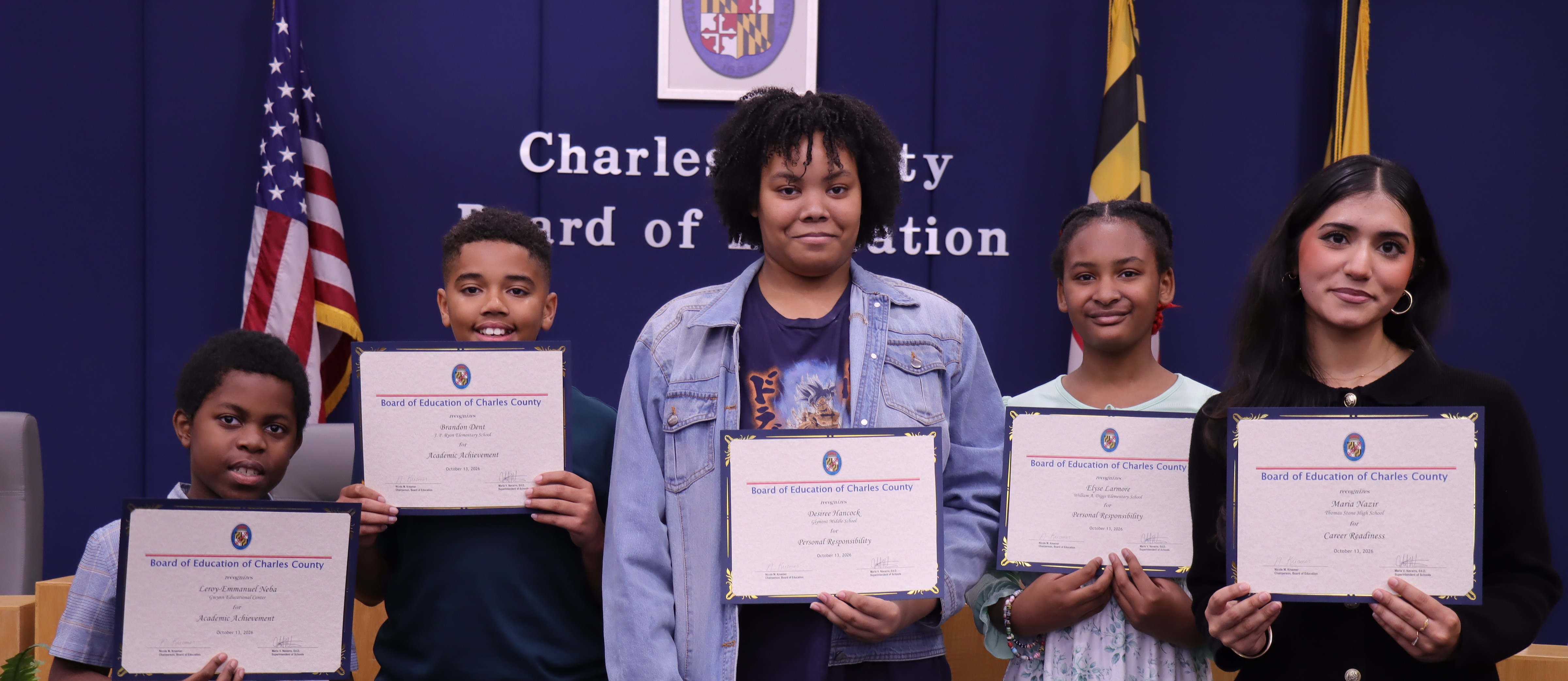 Five students in a row holding certificates