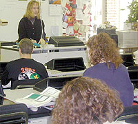 teacher in desk teaching kids at classroom