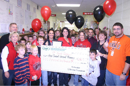 teachers and students holding big check