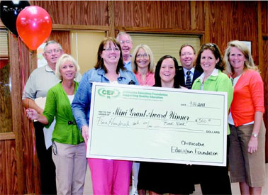 staff taking picture with big check