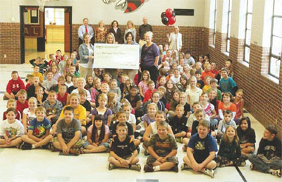 staff and students taking picture with big check