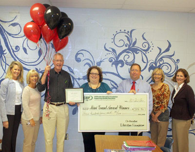 staff taking picture with big check