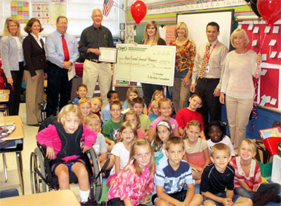 staff and students taking picture with big check