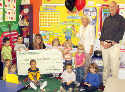 staff and students taking picture with big check