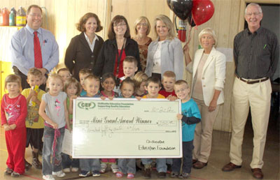 staff and students taking picture with big check