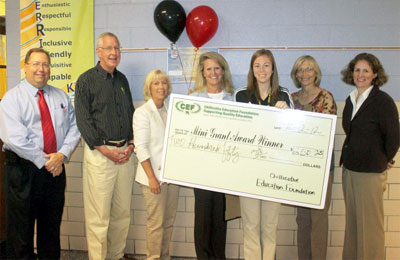 staff taking picture with big check