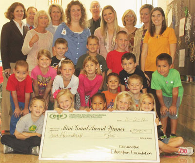 staff and students taking picture with big check