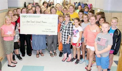 staff and students taking picture with big check