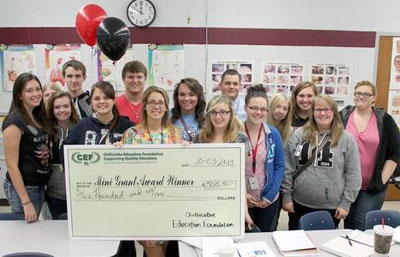 staff and students taking picture with big check