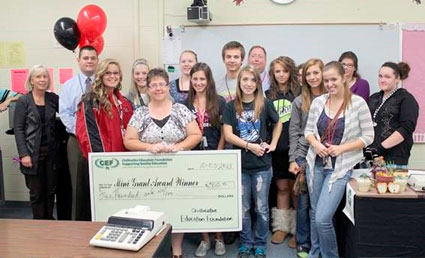 staff and students taking picture with big check