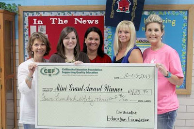 staff and students taking picture with big check