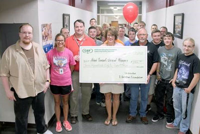 staff and students taking picture with big check